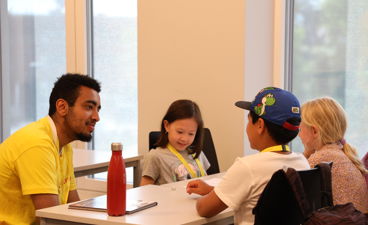 en person og et par barn som sitter ved et bord